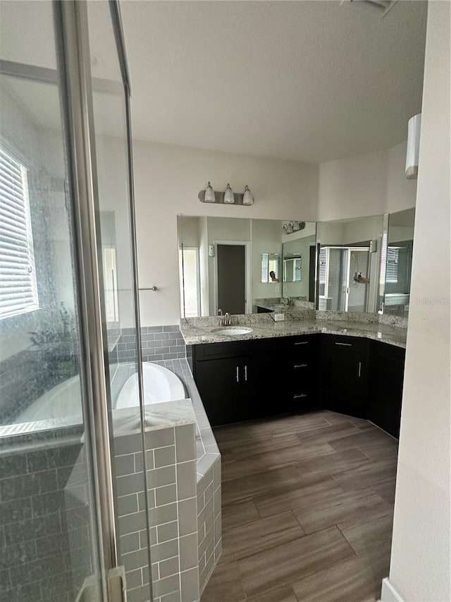 4697 Wandering Way, Wesley Chapel, FL 33544 - full bathroom featuring a shower stall, a bath, vanity, wood finished floors, and a textured ceiling