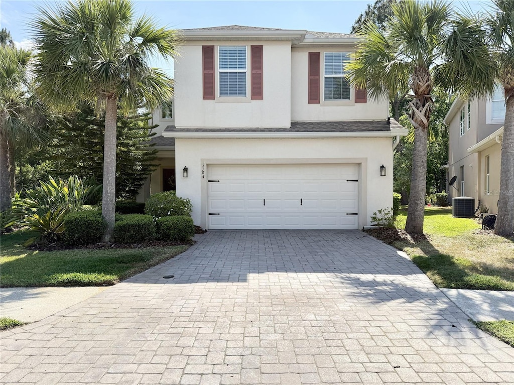 view of front of house featuring an attached garage, central air condition unit, decorative driveway, and stucco siding