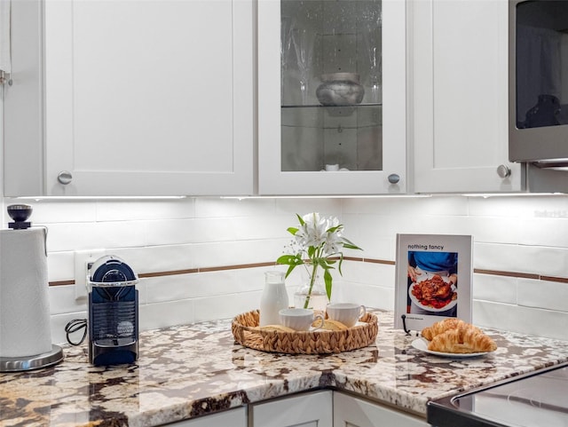11485 Oakhurst Rd Unit 312, Largo, FL 33774 - kitchen view of stainless steel microwave, decorative backsplash, white cabinets, and light stone counters
