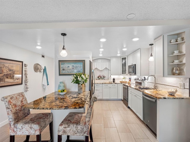 11485 Oakhurst Rd Unit 312, Largo, FL 33774 - kitchen featuring appliances with stainless steel finishes, a sink, glass insert cabinets, pendant lighting, and white cabinets