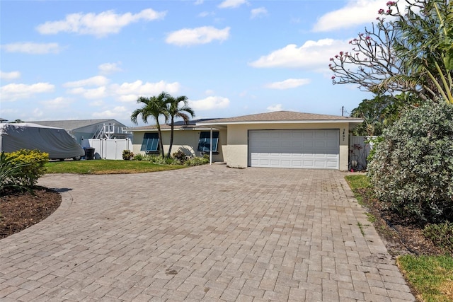 single story home featuring fence, stucco siding, decorative driveway, and a garage