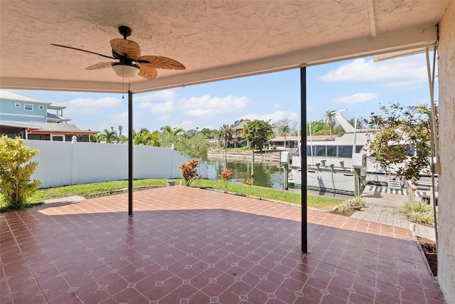 view of patio / terrace featuring a dock, a ceiling fan, boat lift, fence, and a water view