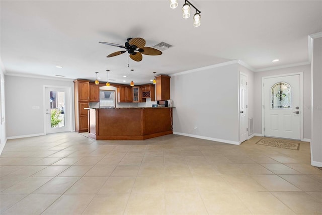 interior space featuring ceiling fan, brown cabinetry, a peninsula, baseboards, and visible vents