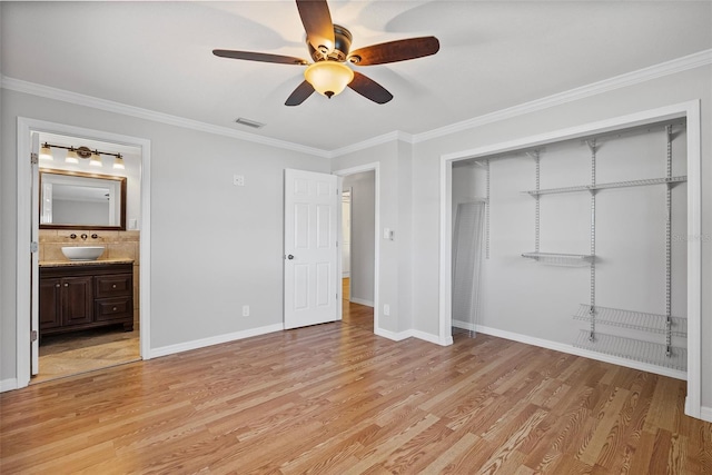 unfurnished bedroom featuring crown molding, a sink, light wood-style floors, visible vents, and a closet