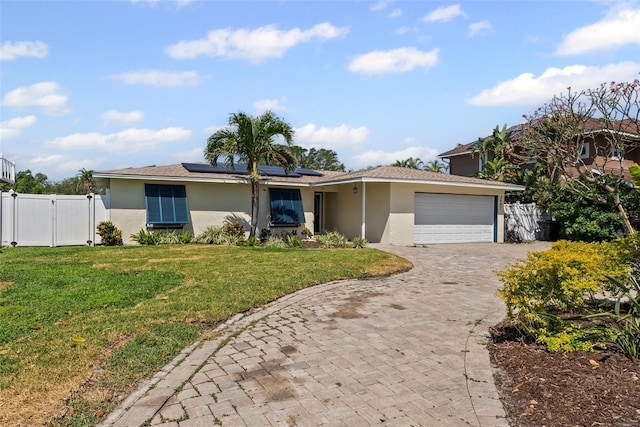 single story home featuring a front yard, a gate, fence, roof mounted solar panels, and stucco siding