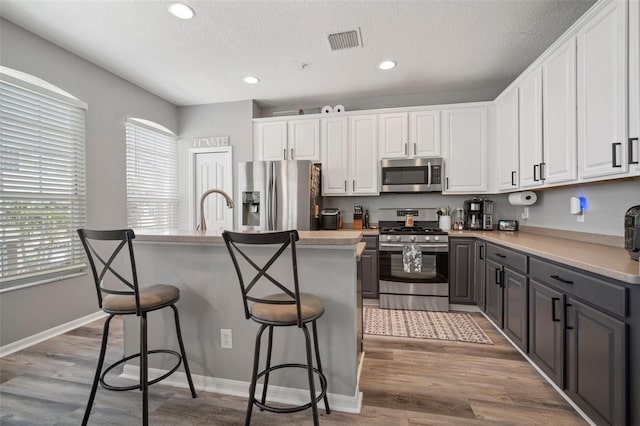 3056 Pointeview Dr, Tampa, FL 33611 - kitchen featuring visible vents, white cabinetry, gray cabinetry, and stainless steel appliances