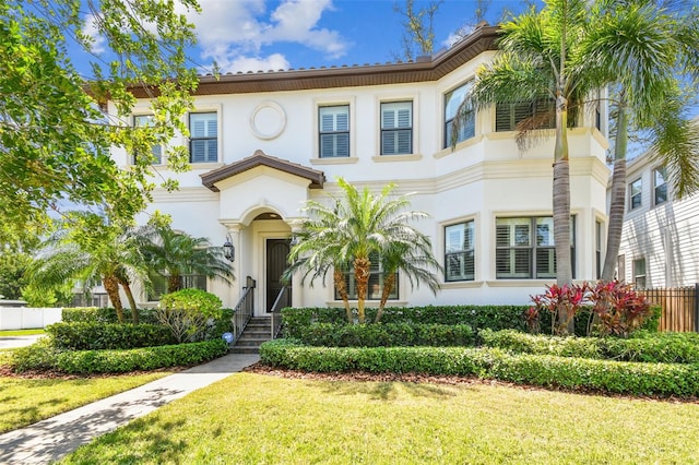 mediterranean / spanish-style house with a front lawn, stucco siding, and fence