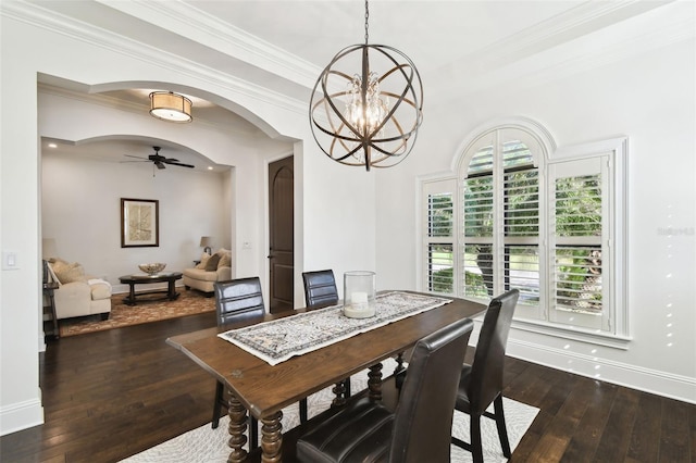 dining room with dark wood-type flooring, crown molding, baseboards, arched walkways, and ceiling fan with notable chandelier