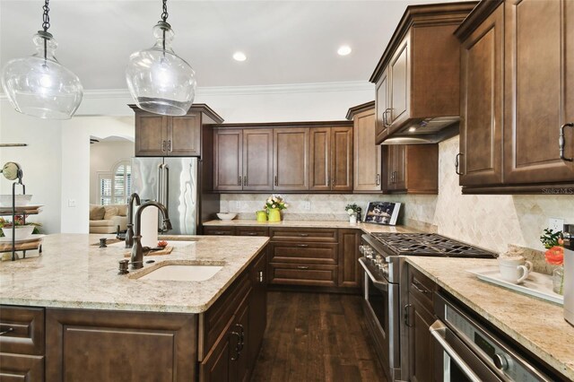 kitchen with light stone countertops, a sink, premium appliances, decorative light fixtures, and dark wood finished floors