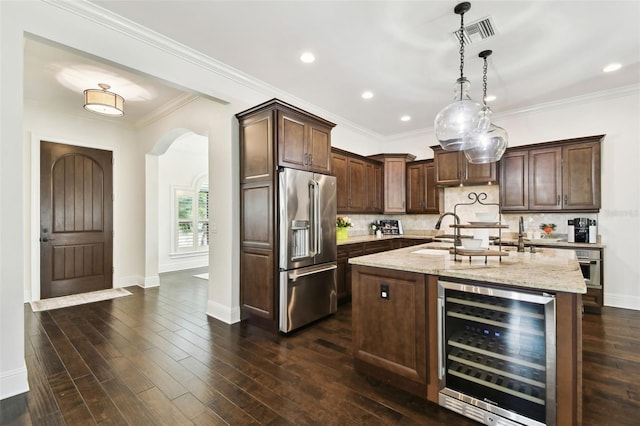 kitchen with beverage cooler, arched walkways, appliances with stainless steel finishes, a sink, and visible vents