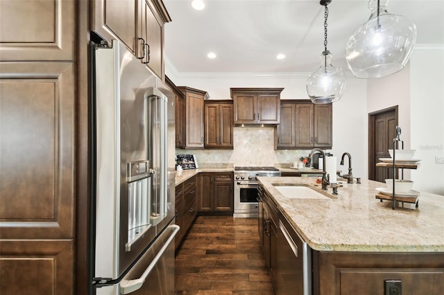kitchen with a kitchen island with sink, light stone counters, high quality appliances, a sink, and dark wood-style floors