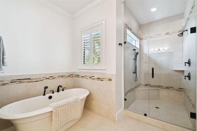 full bathroom featuring tile patterned flooring, a freestanding bath, a shower stall, tile walls, and crown molding
