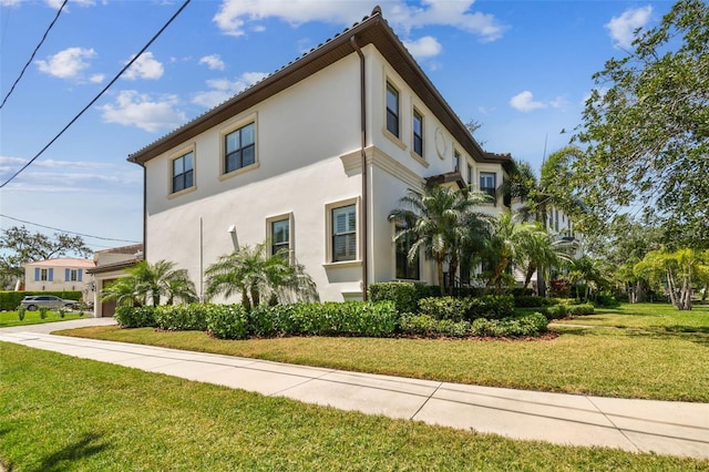 view of side of property with stucco siding, driveway, and a yard