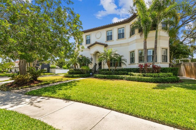 mediterranean / spanish-style home with a front lawn, fence, and stucco siding