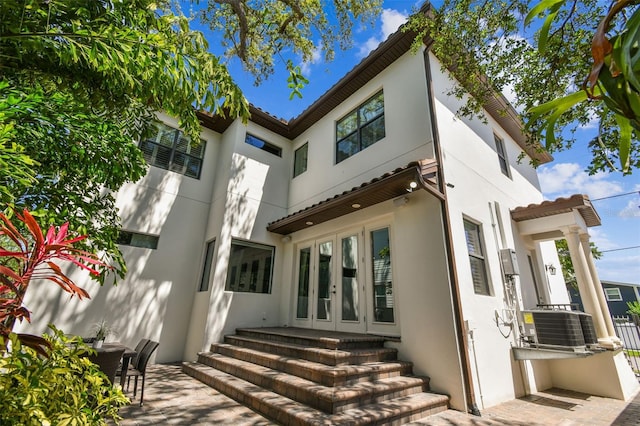 back of house featuring stucco siding, cooling unit, a patio area, and french doors