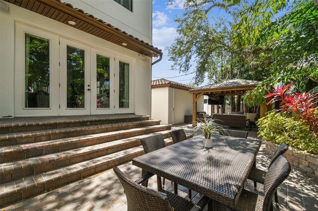 view of patio with an outdoor living space, outdoor dining area, a gazebo, and french doors