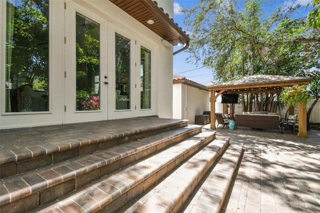 wooden deck featuring a patio, an outdoor living space, a gazebo, and french doors