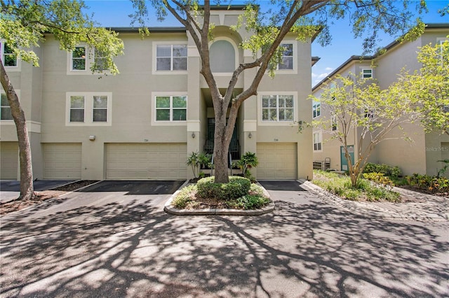 multi unit property featuring stucco siding, an attached garage, and driveway