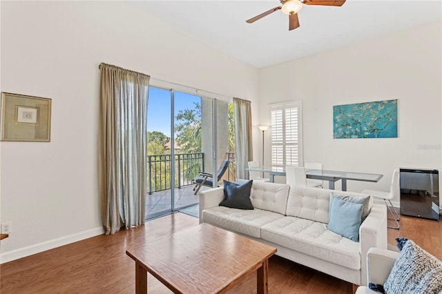 living area featuring a ceiling fan, baseboards, and wood finished floors
