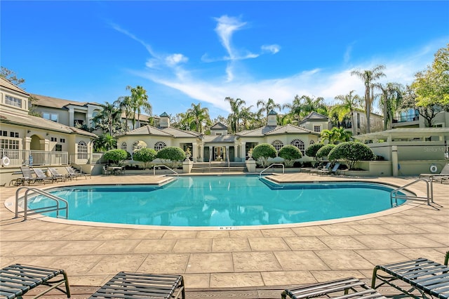pool with a patio, fence, and a residential view