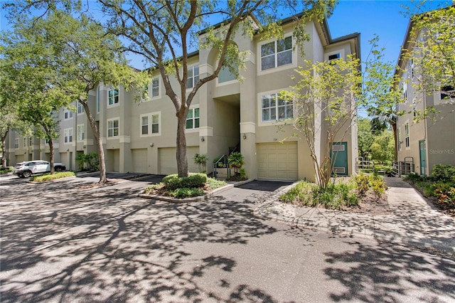multi unit property featuring a residential view, stucco siding, an attached garage, and driveway