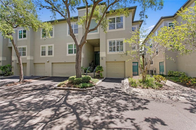 townhome / multi-family property featuring a garage, stucco siding, and driveway