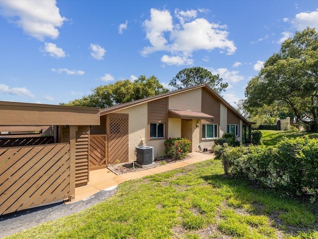 back of property with fence, stucco siding, and central AC