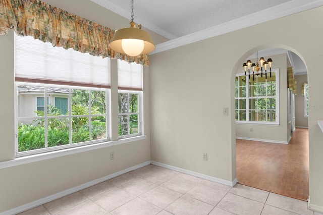 15314 Sherwood Forest Dr, Tampa, FL 33647 - unfurnished dining area featuring a chandelier, arched walkways, crown molding, light tile patterned floors, and baseboards