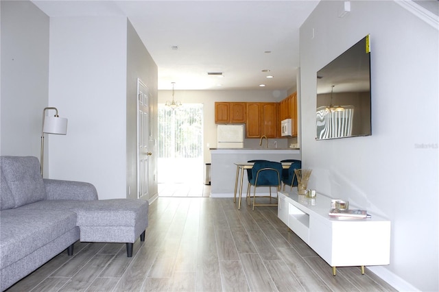 living area featuring an inviting chandelier, light wood-type flooring, recessed lighting, and baseboards