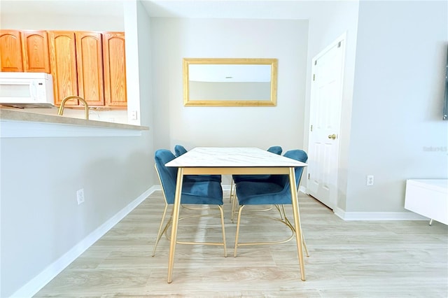 dining area with light wood finished floors and baseboards