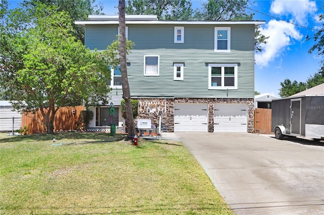 view of front of property featuring a front lawn, a garage, driveway, stone siding, and fence