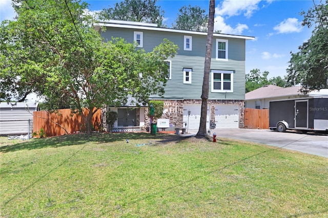 view of front of house featuring driveway, stone siding, fence, a front lawn, and a garage