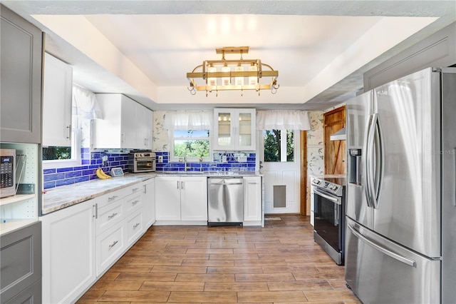 kitchen featuring a sink, wood finished floors, stainless steel appliances, and plenty of natural light