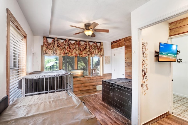 bathroom with ceiling fan, wood walls, and wood finished floors
