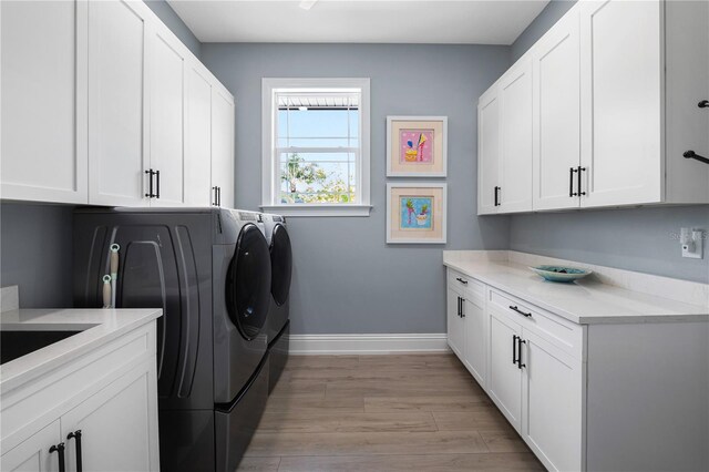 17305 Ballmont Park Dr, Odessa, FL 33556 - laundry area featuring light wood finished floors, washer and dryer, cabinet space, and baseboards