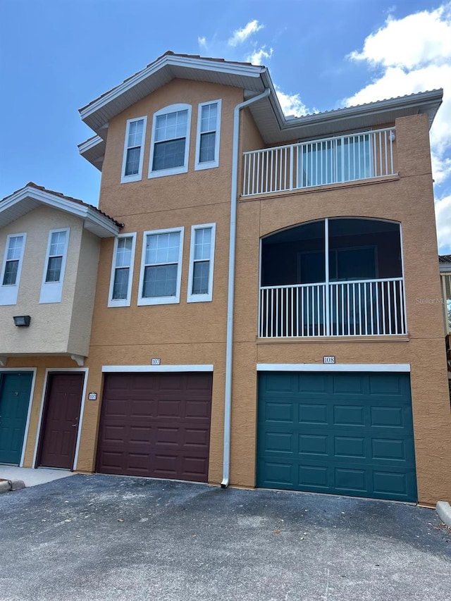 multi unit property featuring a garage, stucco siding, and a balcony