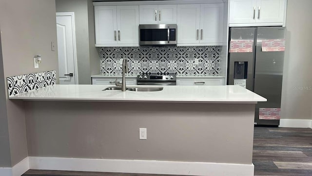 kitchen with tasteful backsplash, a sink, stainless steel appliances, light countertops, and dark wood finished floors