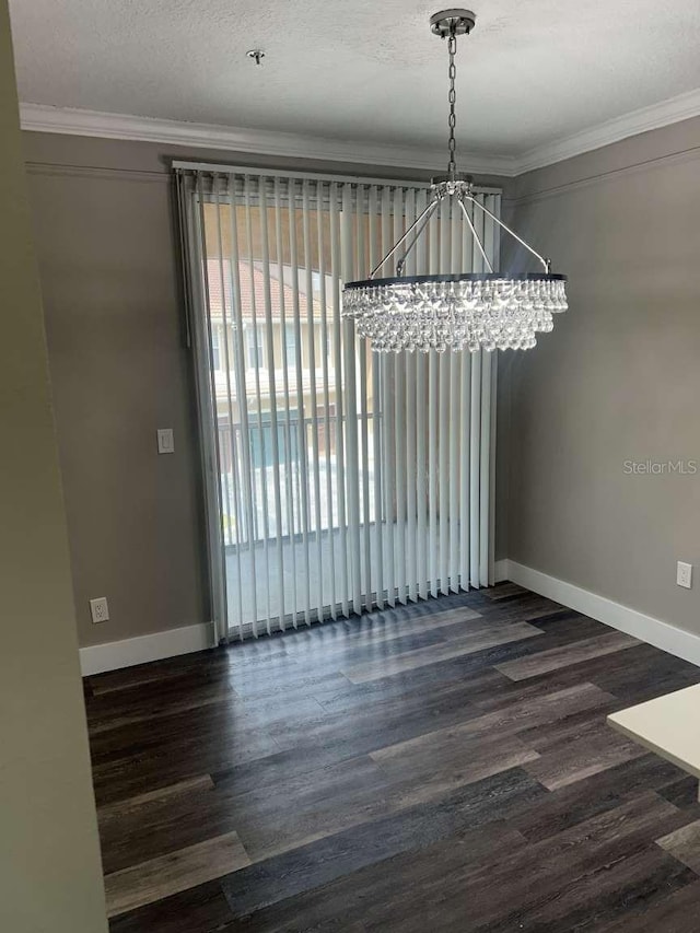 unfurnished dining area with wood finished floors, crown molding, a notable chandelier, and baseboards
