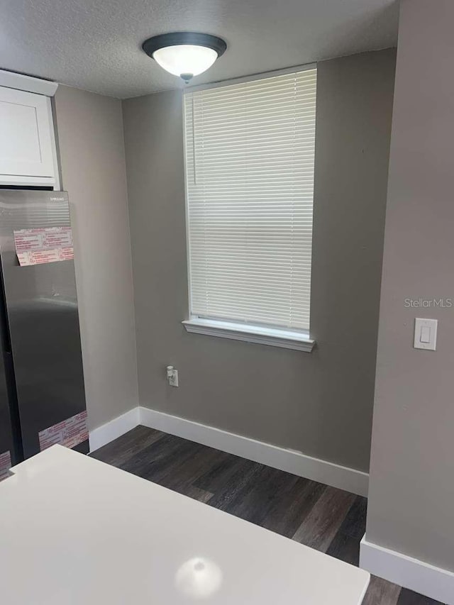 unfurnished dining area featuring dark wood finished floors and baseboards