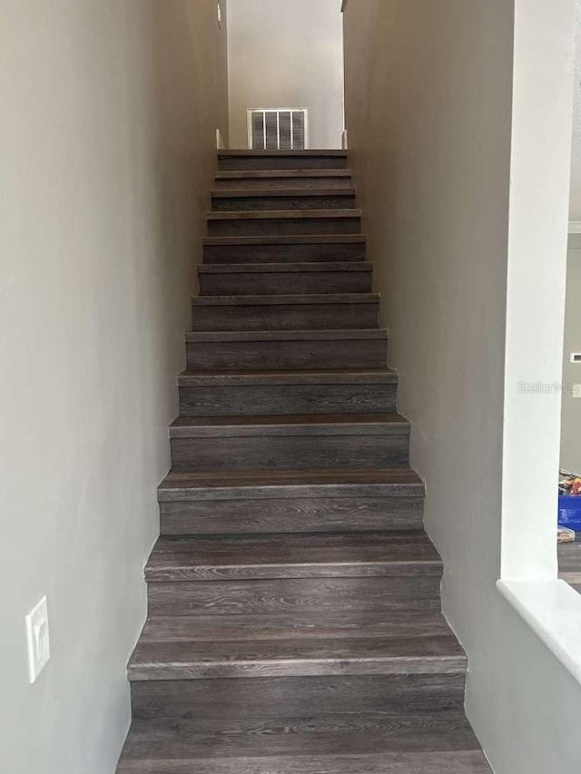 stairway featuring wood finished floors and visible vents
