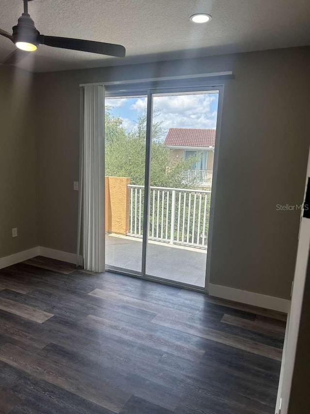spare room featuring dark wood-style floors, a ceiling fan, a textured ceiling, and baseboards