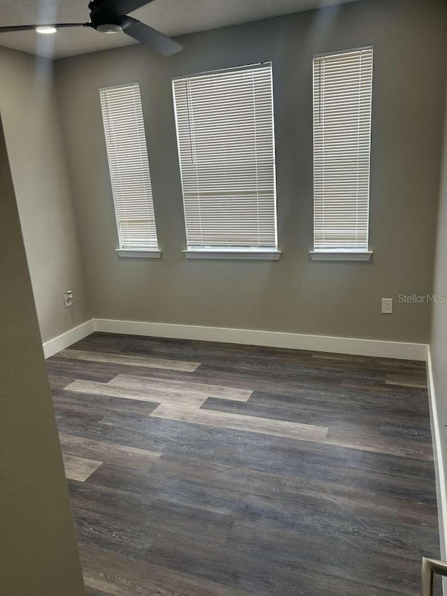 empty room with ceiling fan, dark wood-style floors, and baseboards