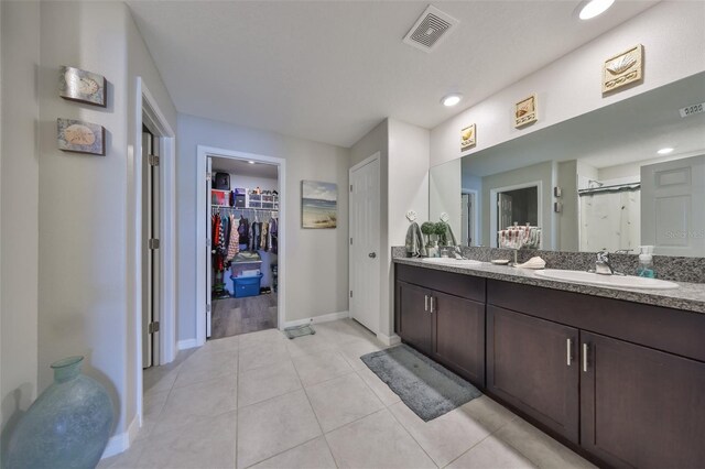 15426 Wicked Strong St, Sun City Center, FL 33573 - full bathroom featuring baseboards, double vanity, a walk in closet, a shower stall, and tile patterned flooring