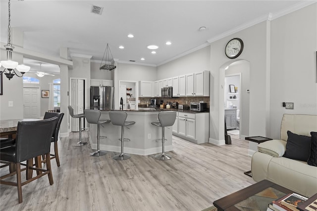 9723 Rolling Cir, San Antonio, FL 33576 - living room with arched walkways, ornamental molding, light wood-type flooring, and visible vents