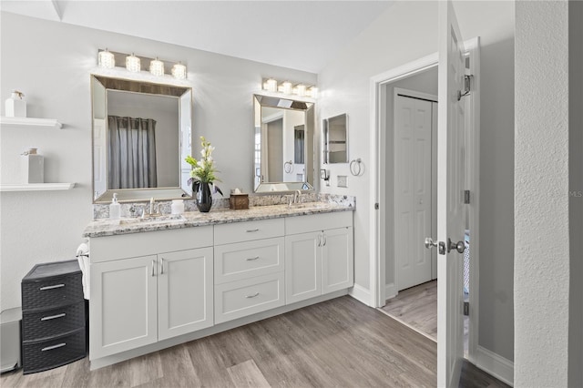 9723 Rolling Cir, San Antonio, FL 33576 - bathroom with a sink, double vanity, vaulted ceiling, and wood finished floors