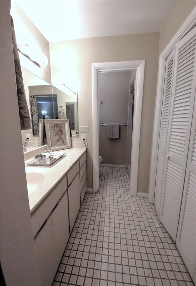 bathroom with vanity, toilet, tile patterned flooring, and a closet