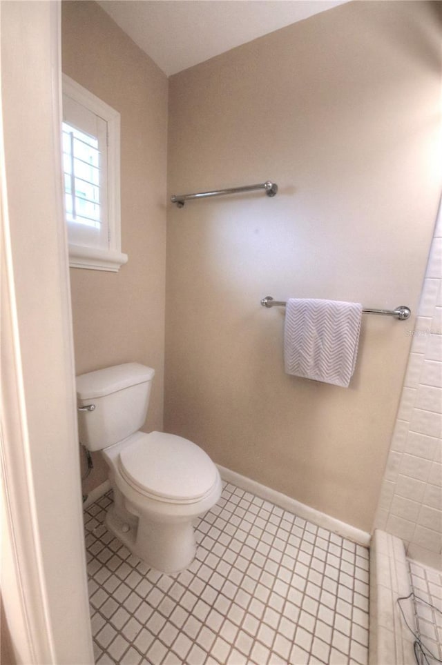 bathroom featuring toilet, baseboards, and tile patterned flooring