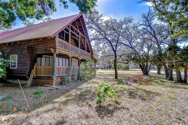 4126 Burrows Rd, Zephyrhills, FL 33542 - view of property exterior featuring metal roof, a balcony, and log exterior