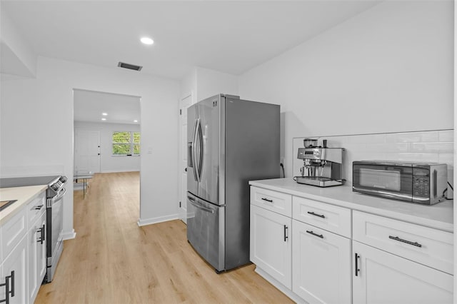 1225 58th St N Unit 204A, Saint Petersburg, FL 33710 - kitchen featuring stainless steel appliances, white cabinets, light wood-type flooring, recessed lighting, and light countertops