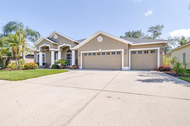 view of front of home with a front yard, driveway, an attached garage, and stucco siding